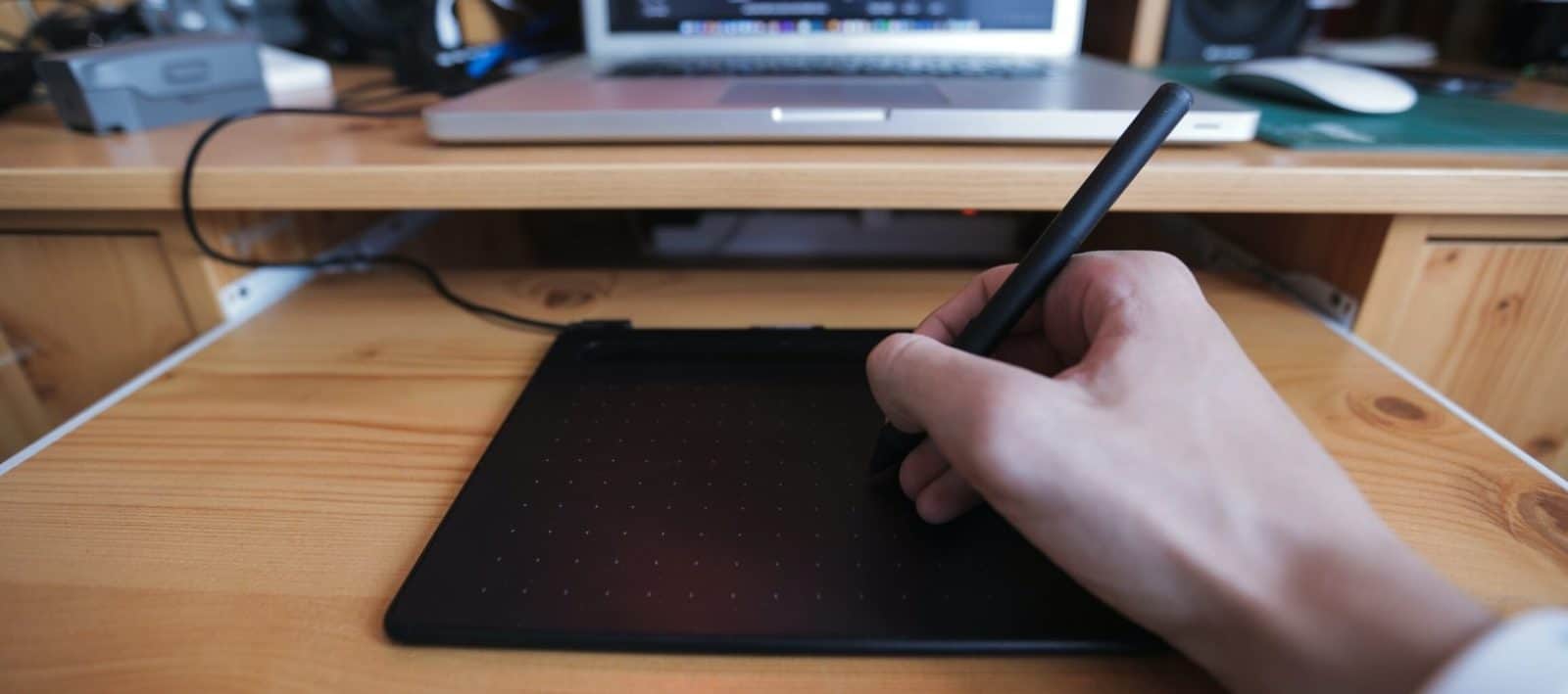hand using a graphic design pen macbook background